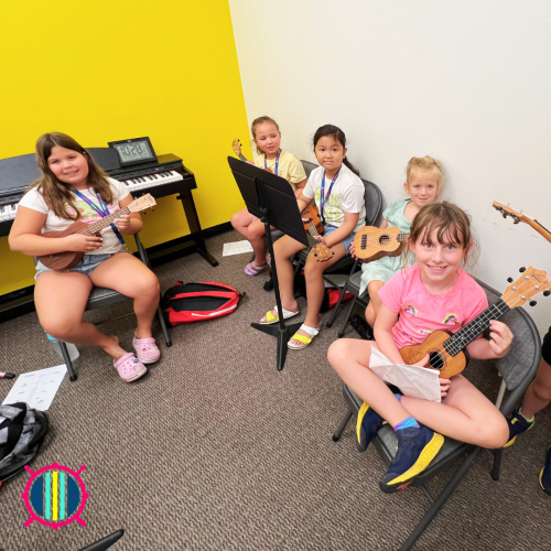 Five children sitting and holding ukuleles